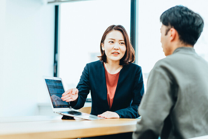 パソコンの画面を見せながら説明する女性